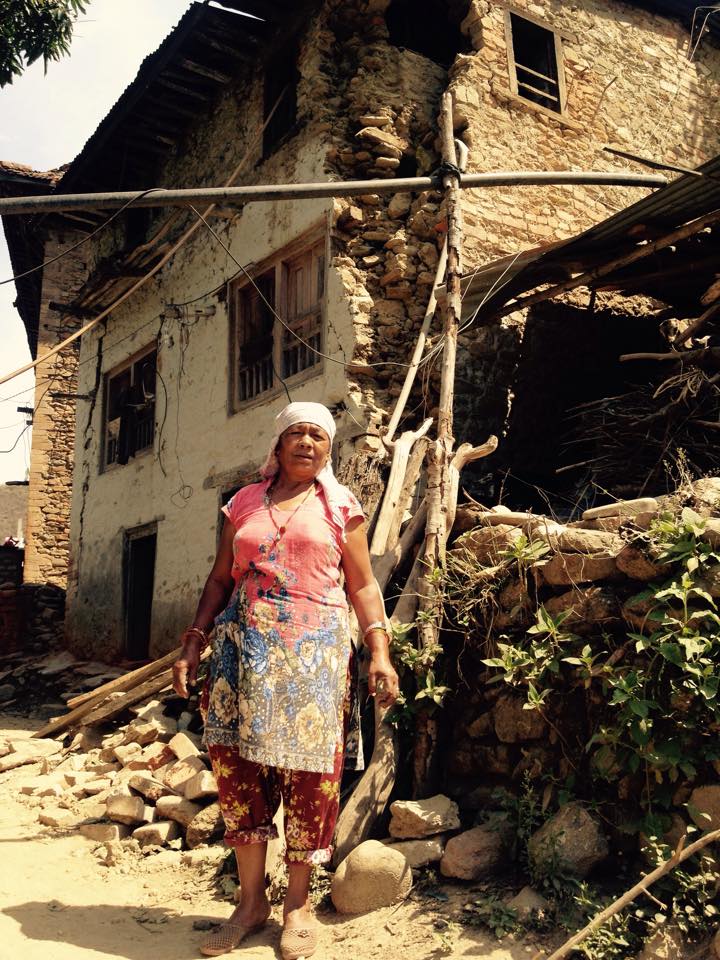 Krishna's mother in front of their massively damaged house